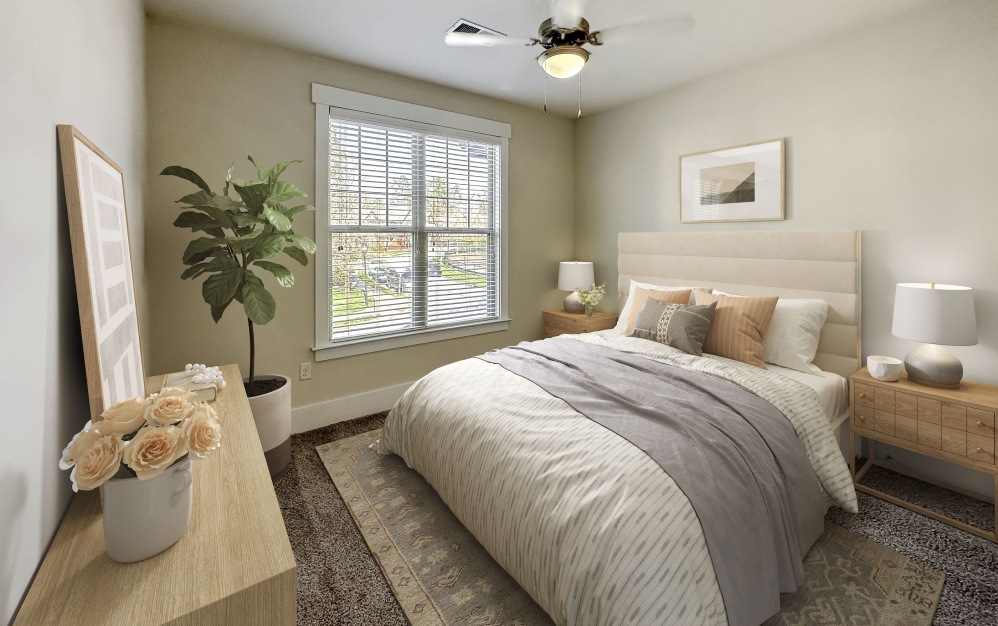 Bedroom with king sized bed, large window, carpet, and end tables with lamps at The Townhomes at Chapel Watch Village