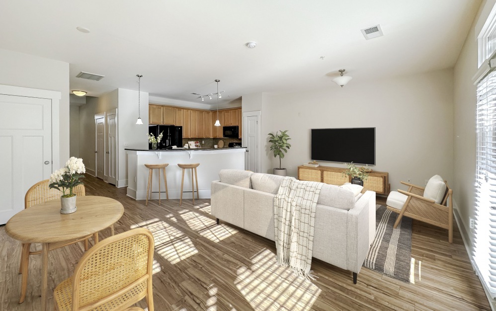 Living area with couch, wall mounted TV, and a dining table at The Townhomes at Chapel Watch Village