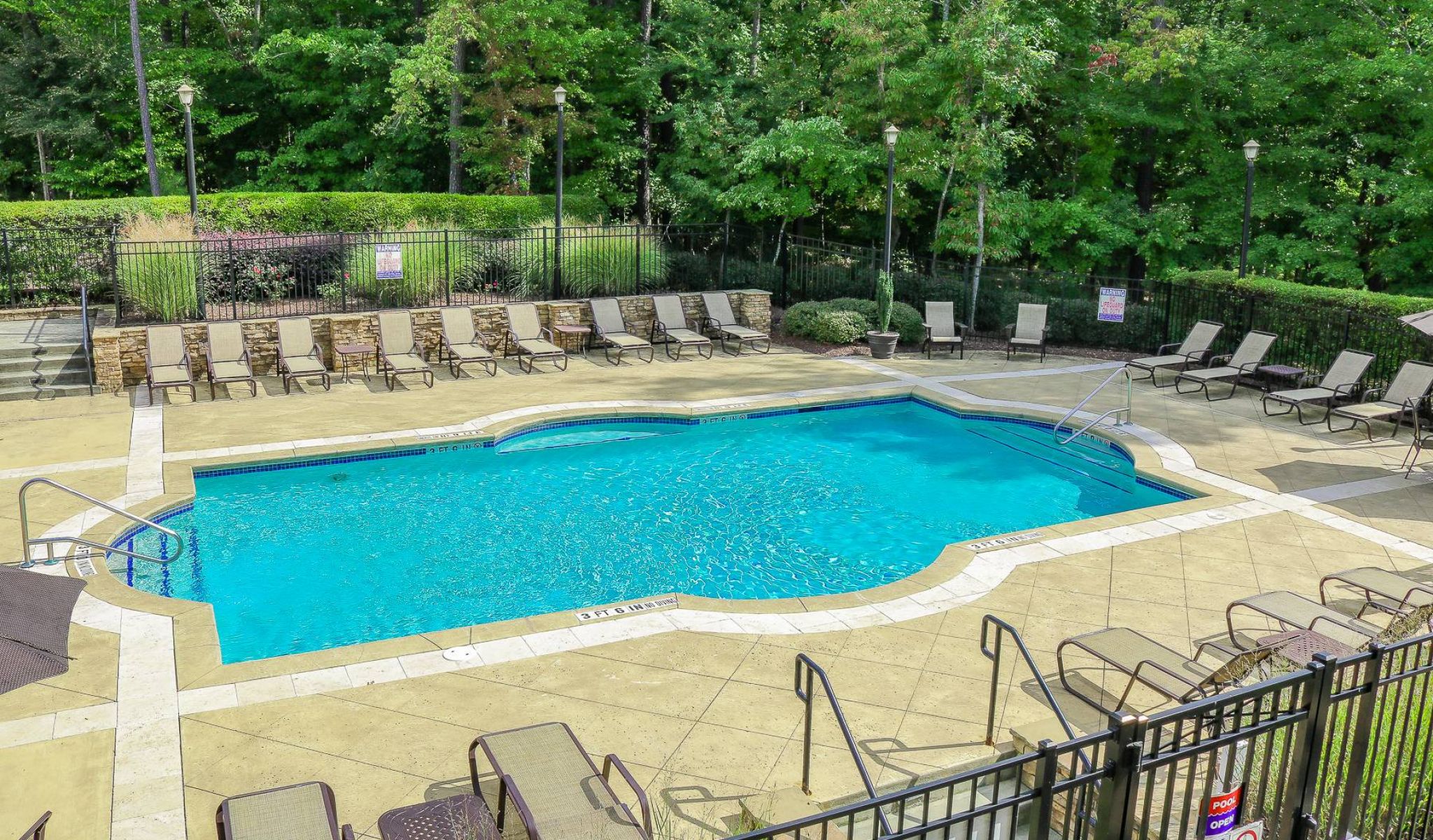 The Townhomes at Chapel Watch Village community saltwater pool and tanning deck surrounded by mature green trees and grass
